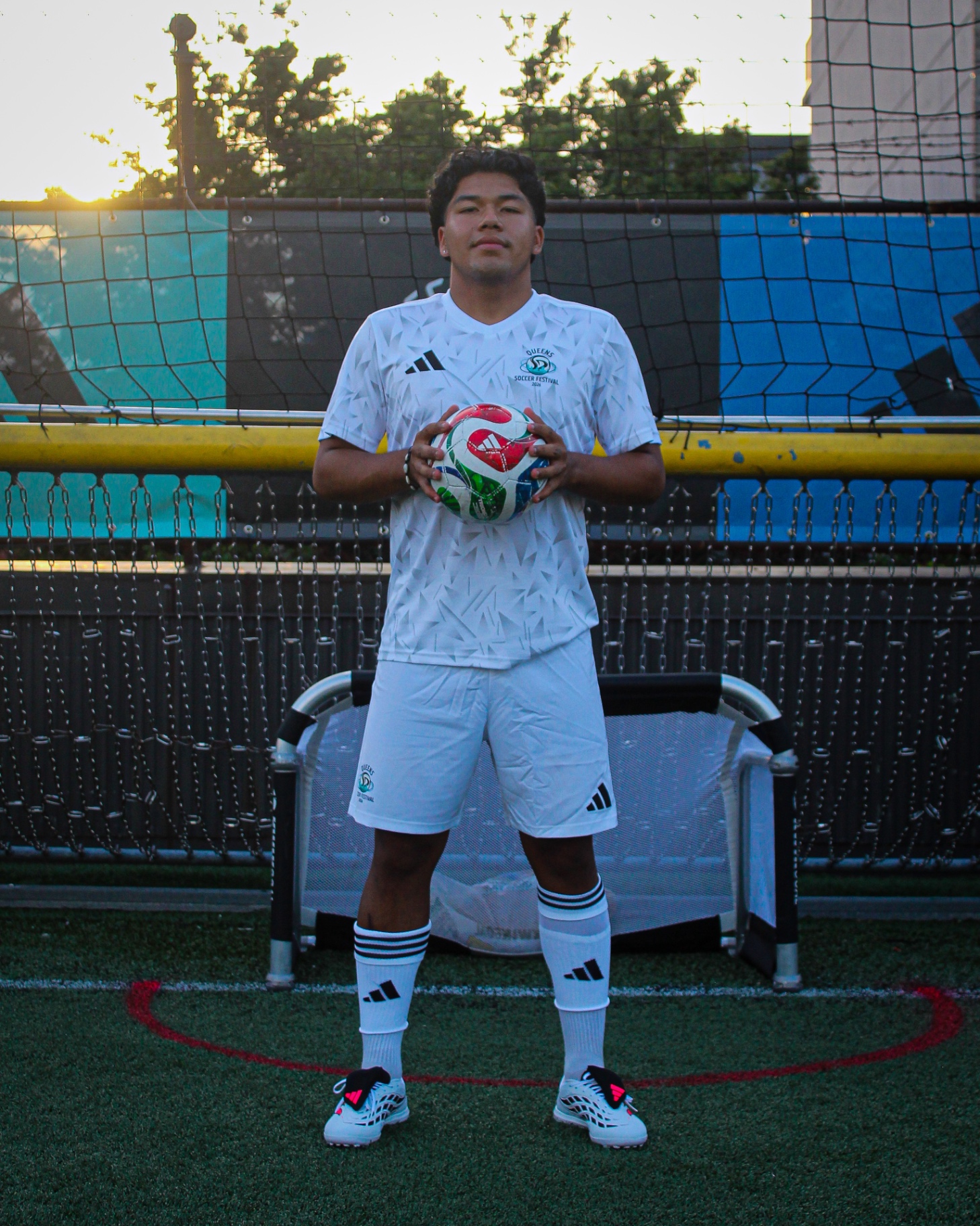 Player portrait in white kit holding ball at sunset